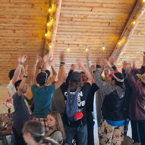 Campers with raised hands in the lodge
